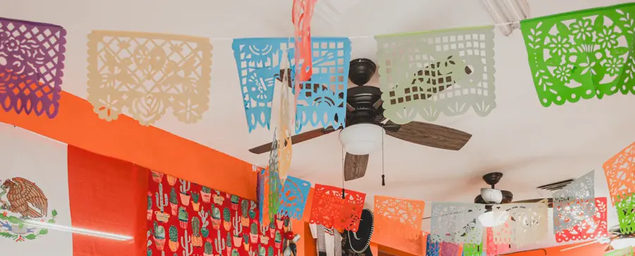 Papel picado banners in orange, blue, green, cream and red hanging over the dining room