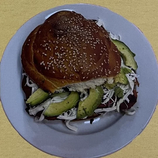 A cemita on a sesame seed roll, with avocado