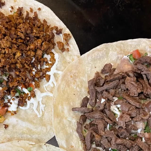 Two burritos cut open, one with al pastor and one with steak