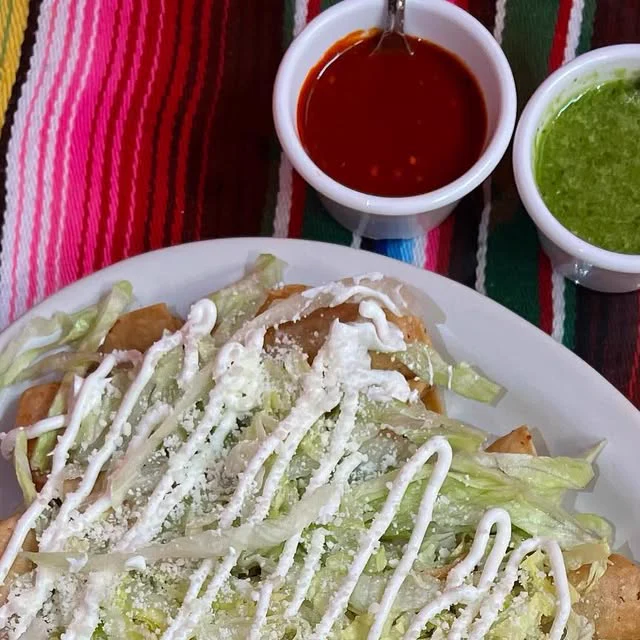 Tacos dorados with lettuce, crema and cheese, and two salsas